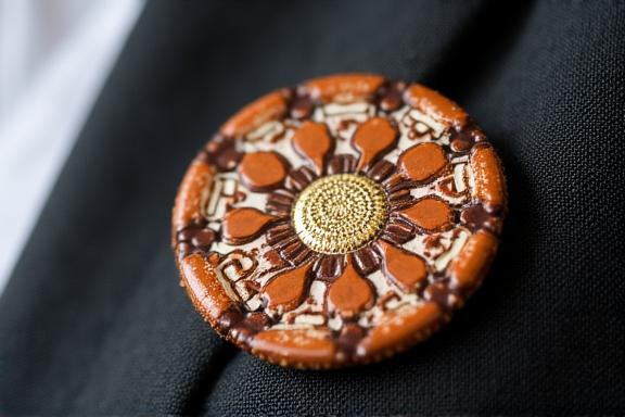 Dettaglio di un blazer con pochette e spilla in ceramica artigianale